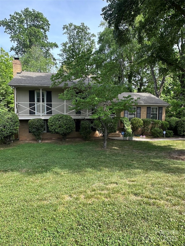 view of front of property with roof with shingles, a chimney, and a front lawn