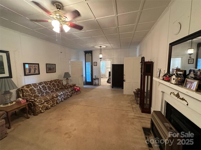 living area featuring ceiling fan, light colored carpet, and a fireplace