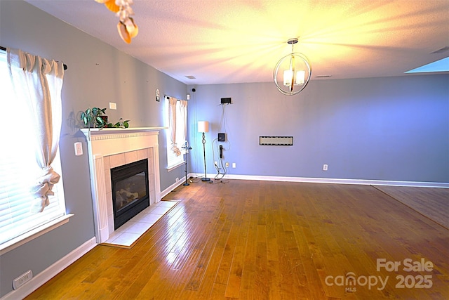 6614 Wicked Oak Ln, Charlotte, NC 28216 - unfurnished living room featuring hardwood / wood-style floors, a tile fireplace, and a chandelier