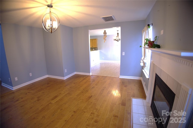 6614 Wicked Oak Ln, Charlotte, NC 28216 - unfurnished living room with a chandelier, light wood-style flooring, and a tile fireplace