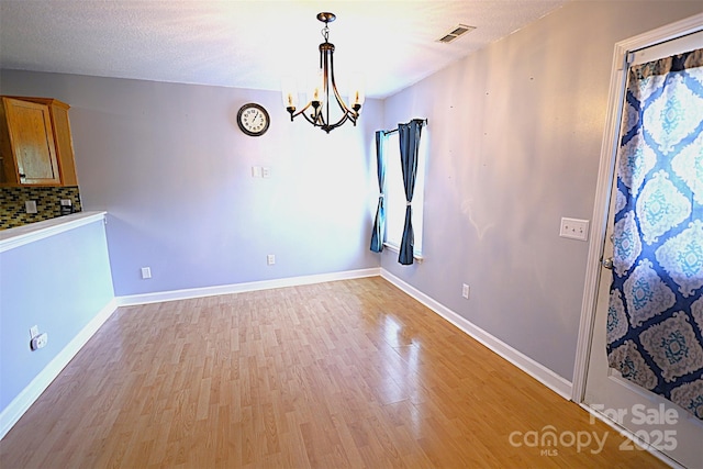 6614 Wicked Oak Ln, Charlotte, NC 28216 - unfurnished dining area with light wood-style floors and a chandelier
