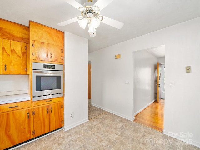 92 Church St, Weaverville, NC 28787 - kitchen with stainless steel oven, brown cabinets, light countertops, ceiling fan, and baseboards