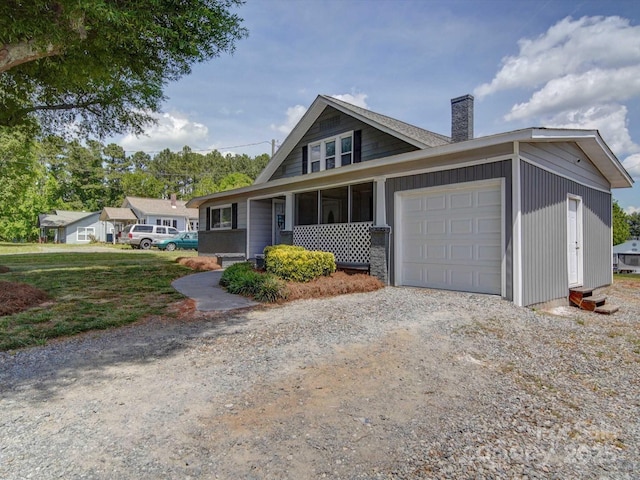 view of front facade featuring a chimney, driveway, and a garage