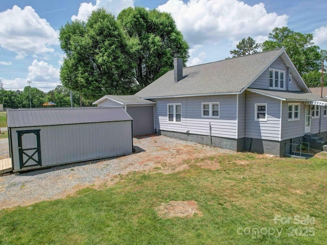 back of house with a yard, a chimney, an outbuilding, and a storage shed