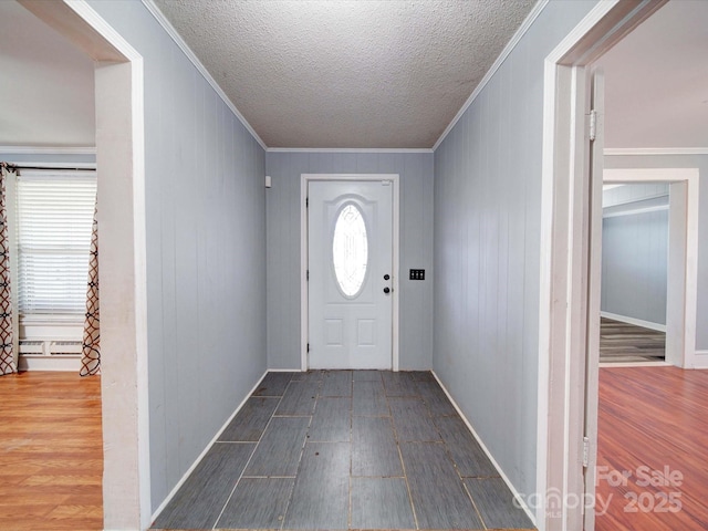 entryway with a baseboard radiator, crown molding, a textured ceiling, and wood finished floors