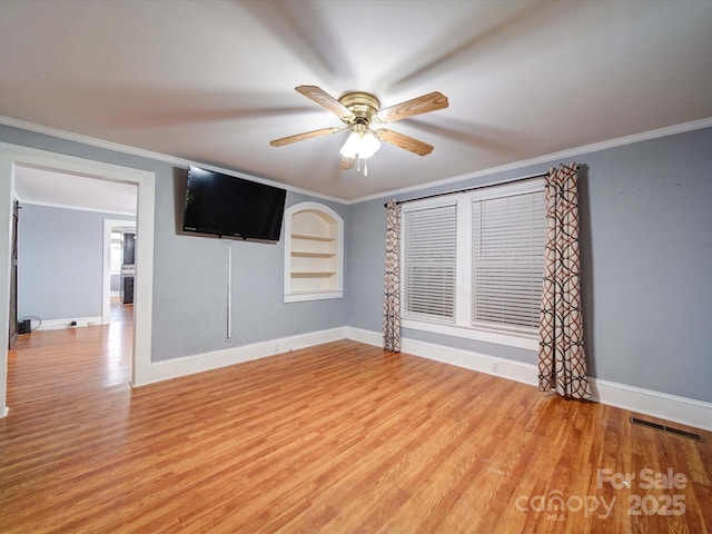 empty room with visible vents, crown molding, a ceiling fan, baseboards, and light wood-style floors