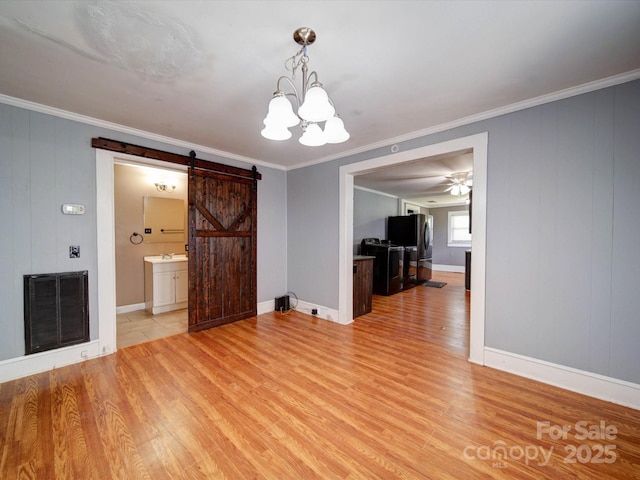 interior space with crown molding, a barn door, visible vents, and light wood-style floors