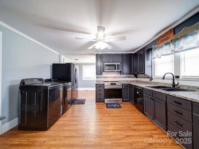 kitchen with washing machine and dryer, a sink, crown molding, light wood-type flooring, and appliances with stainless steel finishes