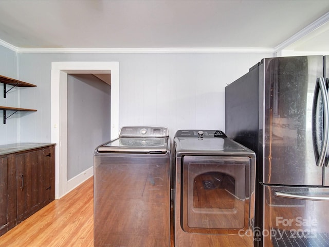 laundry area with baseboards, ornamental molding, separate washer and dryer, laundry area, and light wood-type flooring