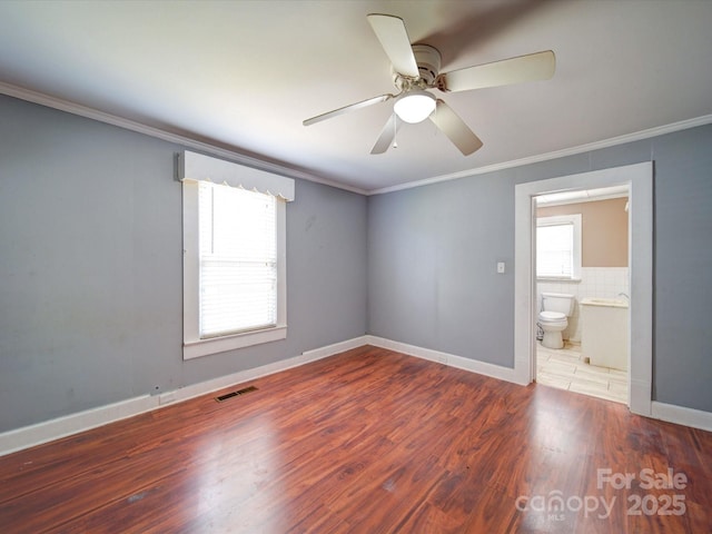 interior space with wood finished floors, visible vents, baseboards, ceiling fan, and ornamental molding
