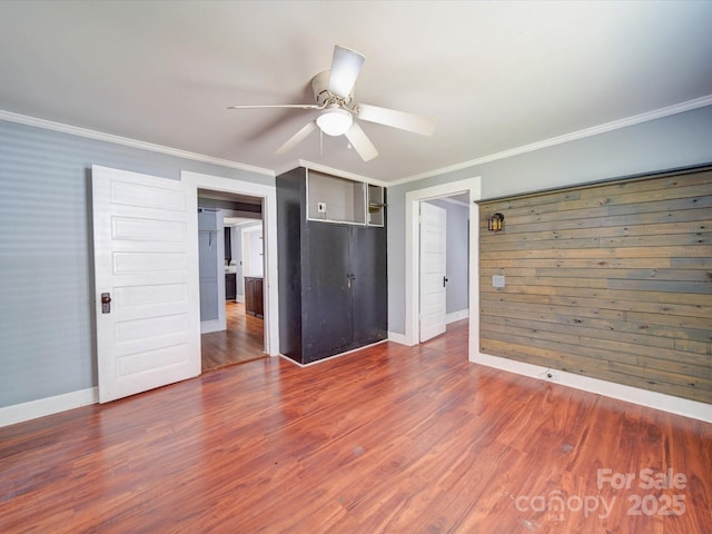 unfurnished living room featuring ornamental molding, wood finished floors, baseboards, and ceiling fan