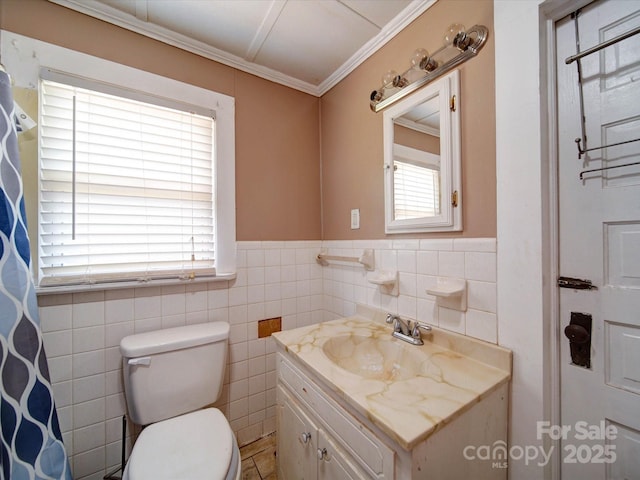 full bath featuring tile walls, toilet, ornamental molding, vanity, and a wainscoted wall