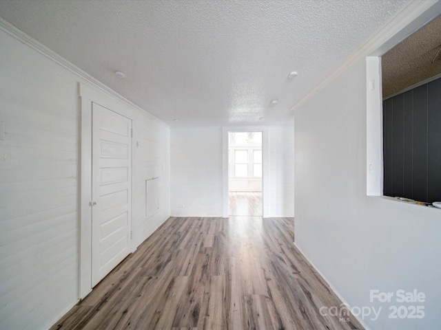 interior space with crown molding, a textured ceiling, and wood finished floors