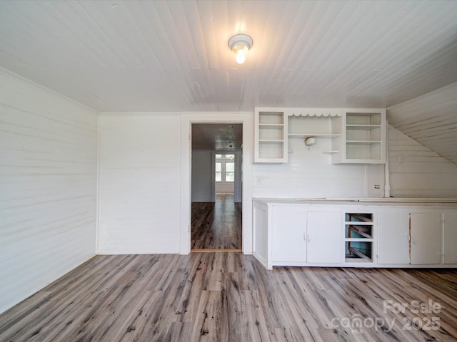 interior space featuring wood finished floors, open shelves, white cabinets, light countertops, and wooden walls