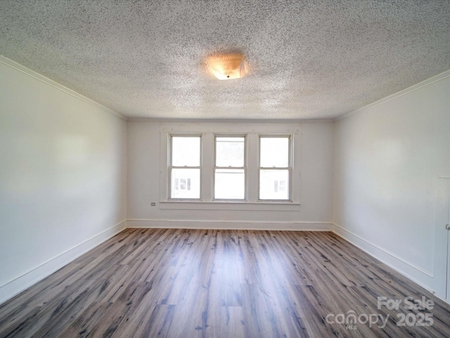 spare room with baseboards, crown molding, a textured ceiling, and wood finished floors