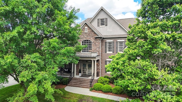 view of front of home featuring stucco siding, stone siding, french doors, and covered porch