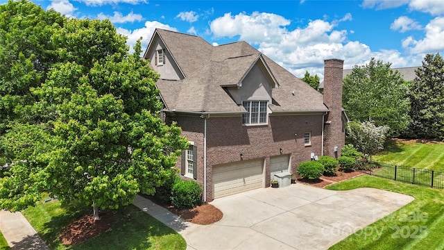view of home's exterior with a chimney, brick siding, a garage, driveway, and a shingled roof