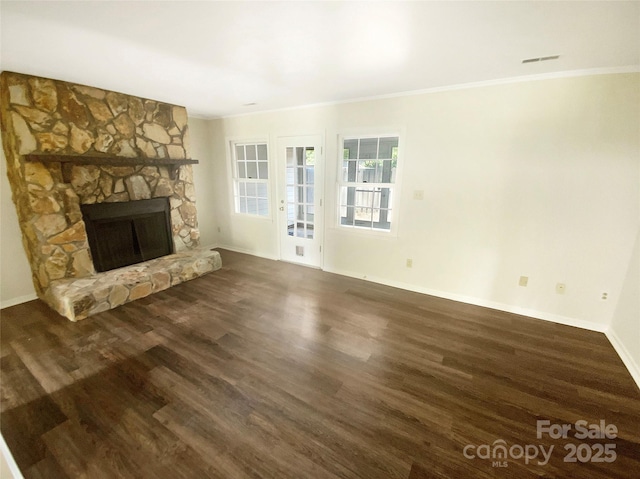 unfurnished living room with a stone fireplace, dark wood-style floors, and ornamental molding