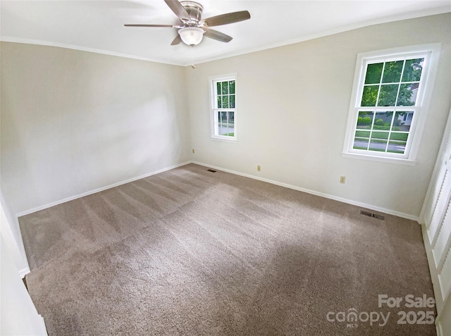 carpeted empty room with crown molding, baseboards, ceiling fan, and visible vents
