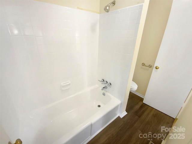 bathroom with toilet, wood finished floors, and shower / washtub combination