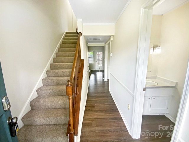 stairs featuring crown molding, wood finished floors, and visible vents