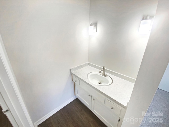 bathroom featuring vanity, baseboards, and wood finished floors