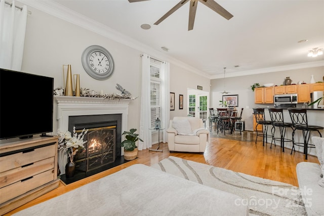 10011 Spring Park Dr, Charlotte, NC 28269 - living room featuring ornamental molding, a warm lit fireplace, light wood-style flooring, and ceiling fan