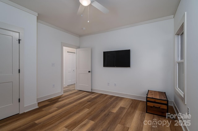 unfurnished bedroom with baseboards, ornamental molding, a ceiling fan, and wood finished floors