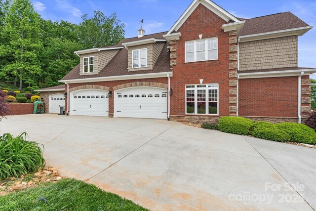 view of front of property featuring concrete driveway, brick siding, and roof with shingles