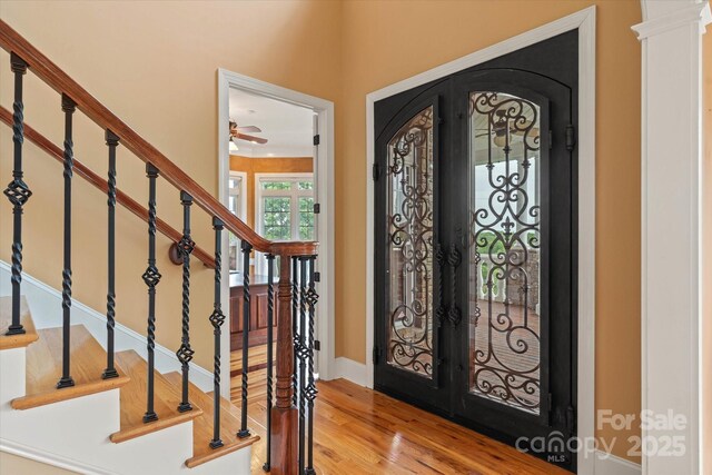entryway featuring light wood-type flooring, arched walkways, stairway, ceiling fan, and baseboards