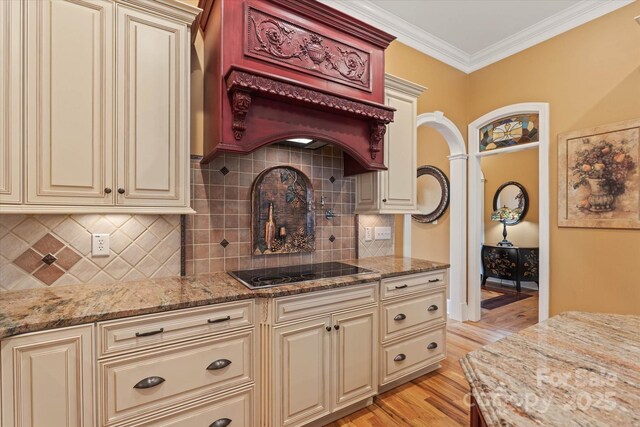 kitchen with cream cabinets, light wood finished floors, light stone countertops, and crown molding
