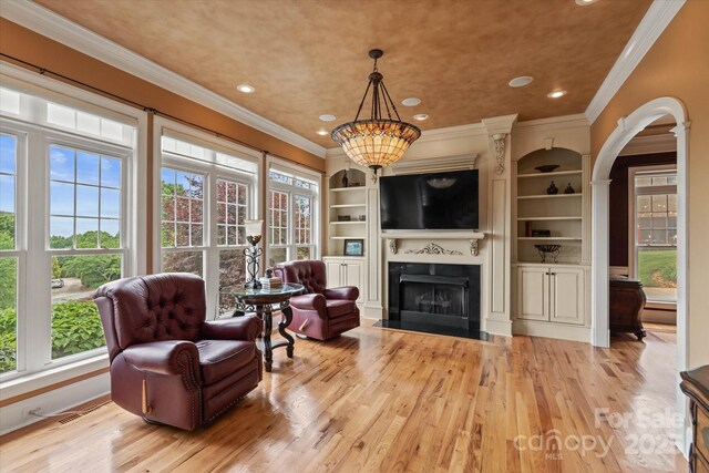 living room featuring ornamental molding, wood finished floors, a fireplace with flush hearth, recessed lighting, and arched walkways