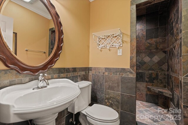 full bathroom featuring tile walls, a sink, walk in shower, wainscoting, and toilet