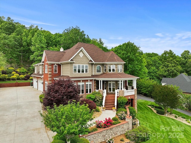 view of front of home with driveway, stairway, a garage, and covered porch
