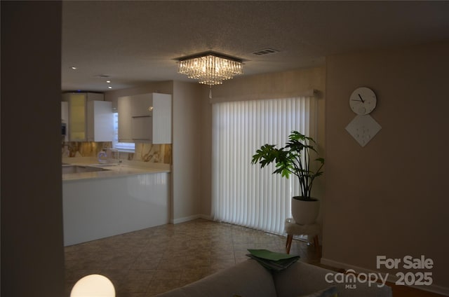 interior space with visible vents, baseboards, a chandelier, and a wealth of natural light