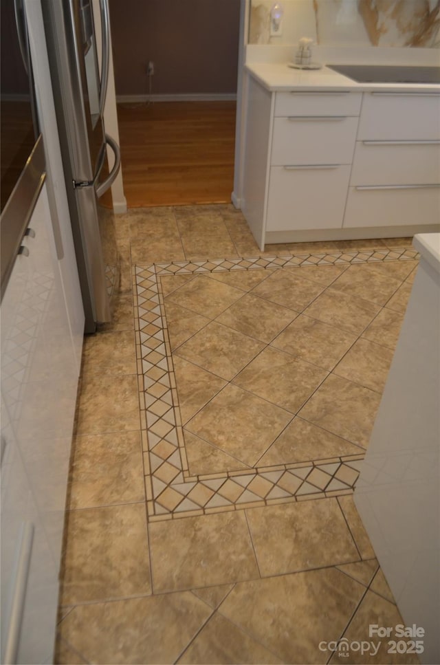 kitchen with freestanding refrigerator, light tile patterned floors, white cabinets, and light countertops