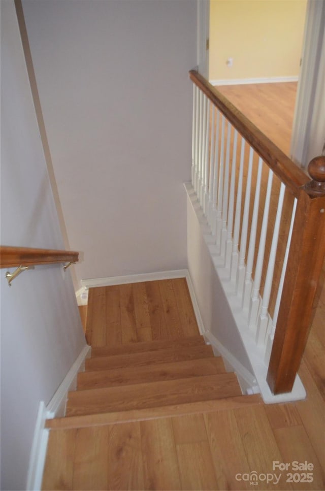 staircase featuring baseboards and wood finished floors