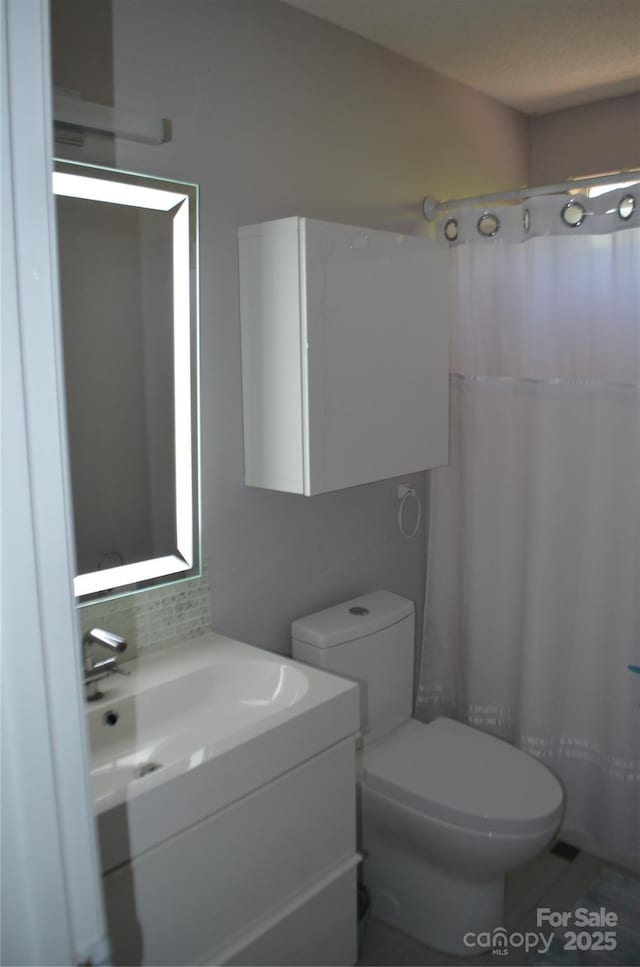 full bath featuring toilet, decorative backsplash, curtained shower, and vanity