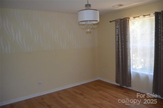 unfurnished dining area featuring baseboards, wood finished floors, and visible vents