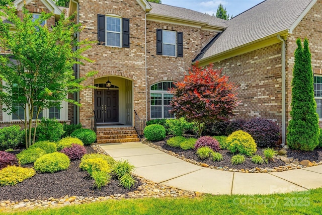 property entrance featuring brick siding and a shingled roof