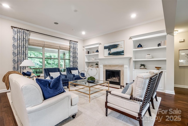 living area featuring crown molding, a fireplace, baseboards, dark wood-type flooring, and built in features