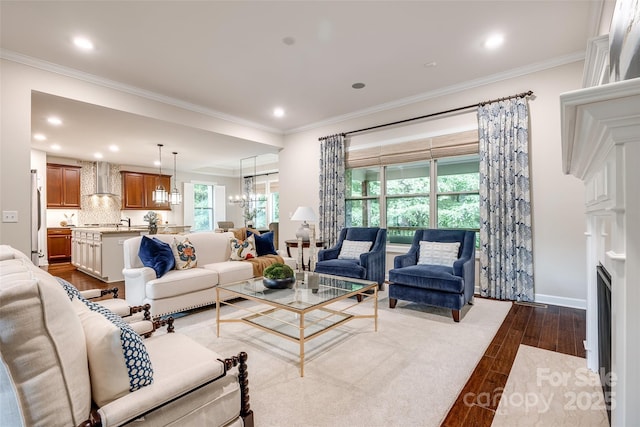 living area with dark wood-style floors, crown molding, recessed lighting, baseboards, and a chandelier