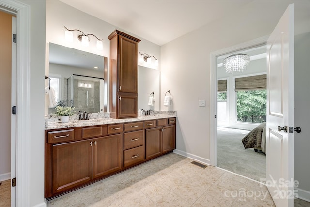 ensuite bathroom with baseboards, double vanity, a chandelier, tile patterned flooring, and a shower with shower door