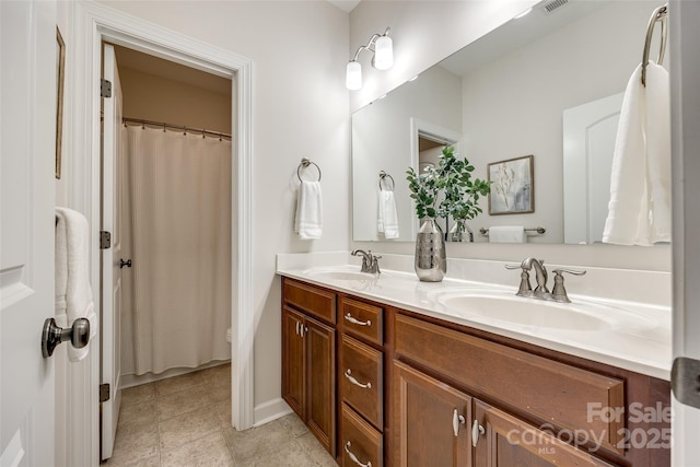 full bath with double vanity, tile patterned flooring, and baseboards