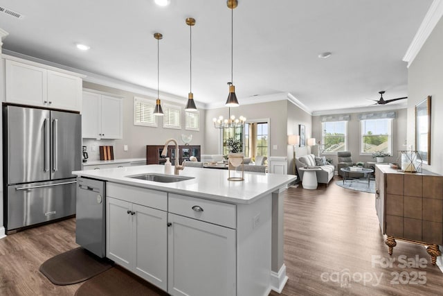 kitchen with a sink, stainless steel appliances, open floor plan, visible vents, and ornamental molding