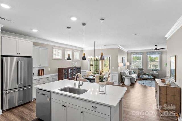 kitchen with dark wood-style flooring, crown molding, a sink, light countertops, and stainless steel appliances