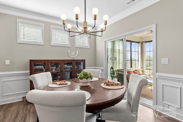 dining room featuring wainscoting, wood finished floors, a notable chandelier, ornamental molding, and a decorative wall