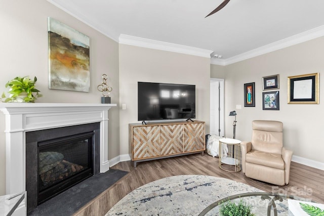 living area featuring crown molding, baseboards, and wood finished floors