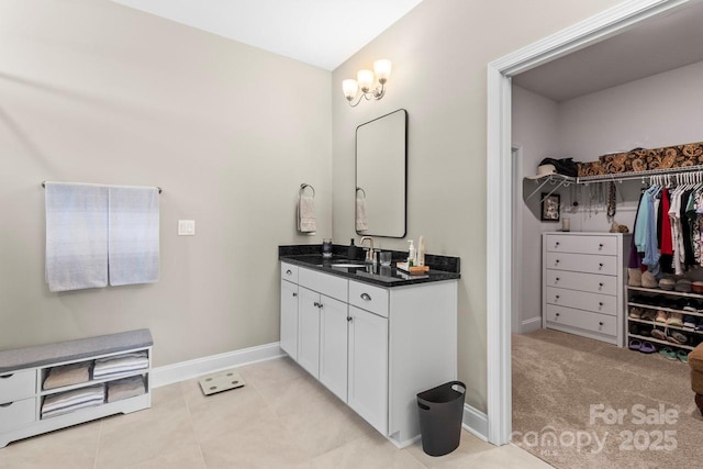 full bathroom featuring baseboards, a spacious closet, and vanity
