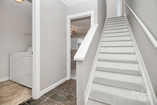 stairs with baseboards, stone finish flooring, ceiling fan, and washing machine and dryer